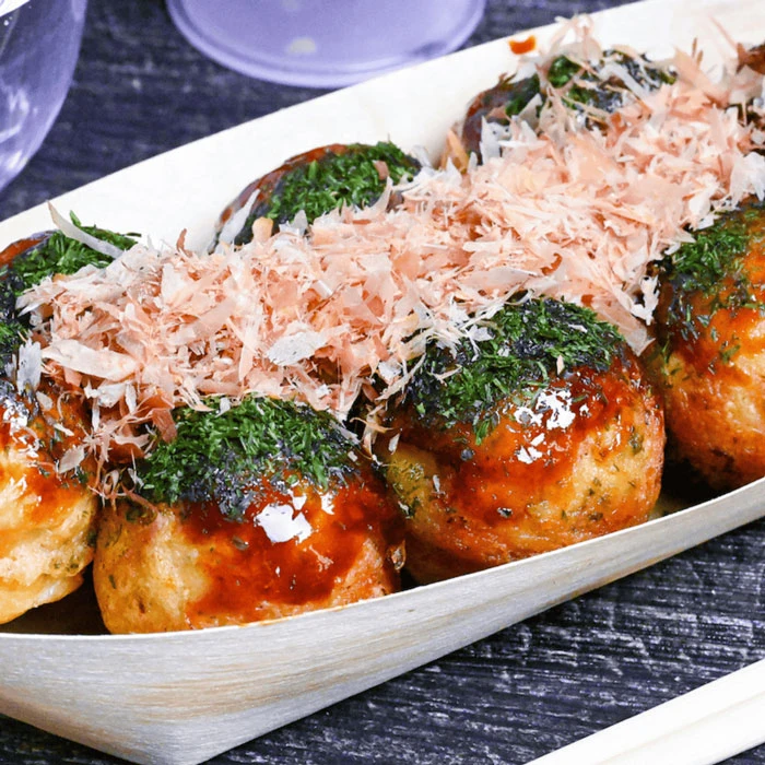 Crispy deep fried takoyaki served in a boat with sauce and bonito flakes in Singapore