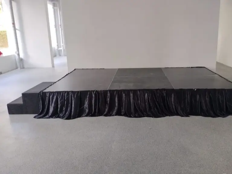 Black platform stage with black skirting and side steps in an open event space in Singapore