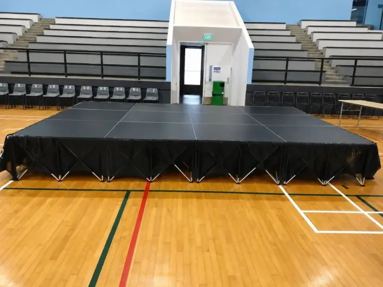 Large black platform stage with black skirting set up on an indoor sports hall court in Singapore