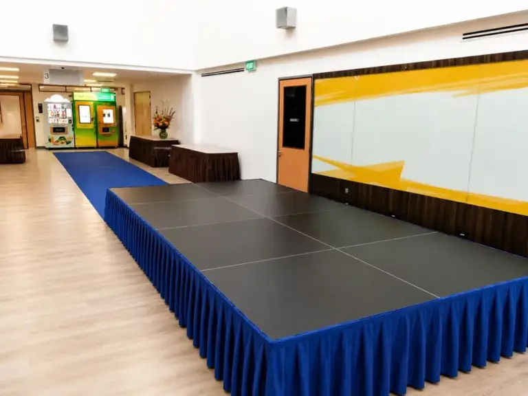Black platform stage with royal blue pleated skirting and a blue carpet aisle in a Singapore event hall