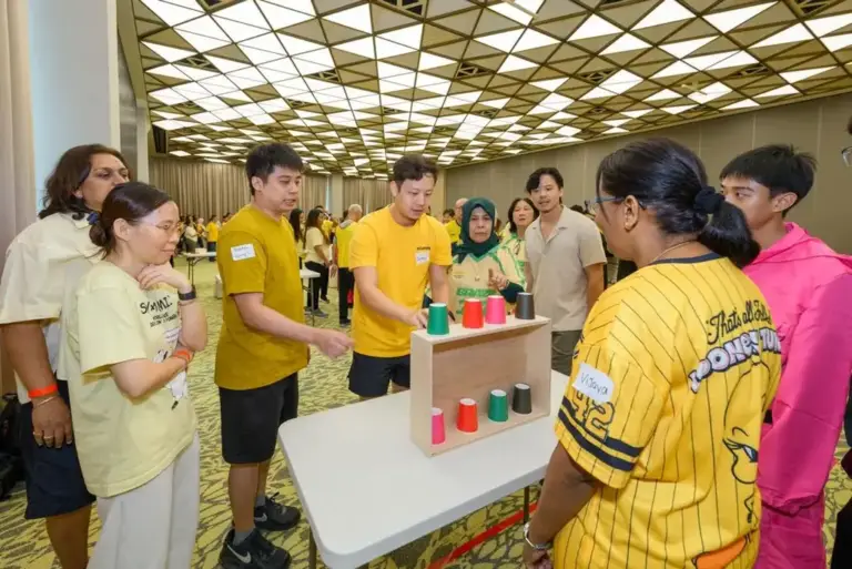 Team solving a coloured cup sequence puzzle at a corporate team building game station in Singapore