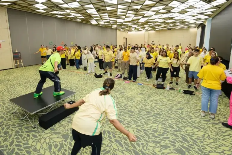 Emcee on stage leading a warm-up for a large corporate team building group in Singapore