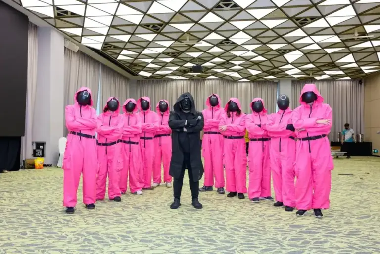 Game master crew in pink jumpsuits and masks for a Squid Game-inspired team building event in Singapore