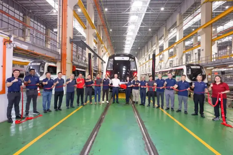 Guests holding a long red ribbon for the cutting moment in front of a new train at a Singapore depot