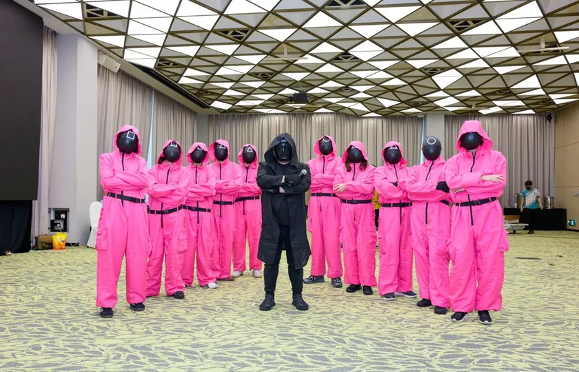 Game master crew in pink jumpsuits and masks for a Squid Game-inspired indoor team building day in Singapore