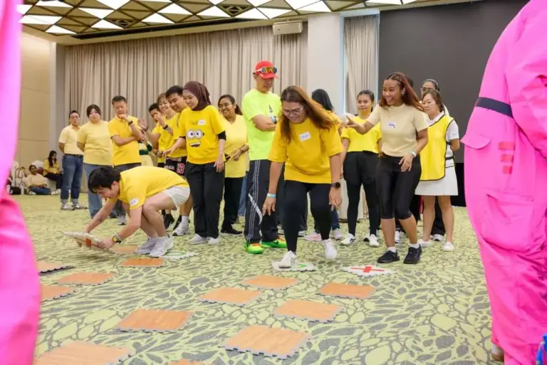 Team members testing floor tiles in a memory tile path game during team building in Singapore