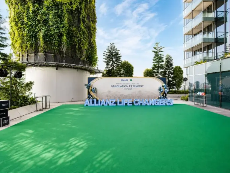 Outdoor graduation ceremony backdrop on a green carpeted rooftop event space in Singapore